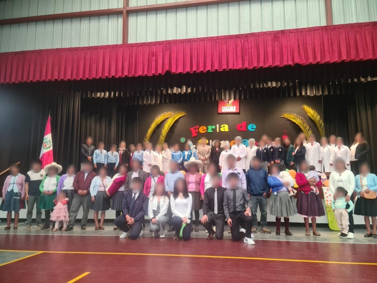 Participantes y familias reunidos en el escenario del coliseo para la foto grupal