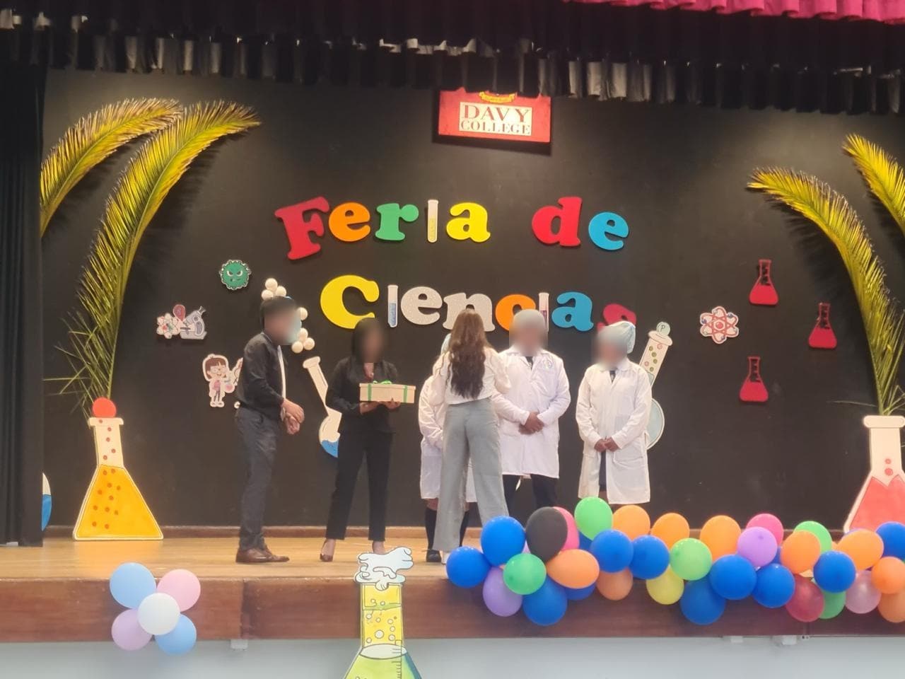 Un equipo de estudiantes recibe su reconocimiento frente al letrero Feria de Ciencias