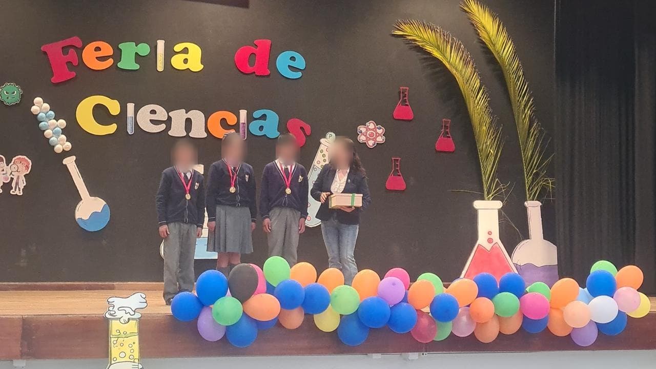 Cuatro estudiantes de uniforme en el escenario decorado con globos